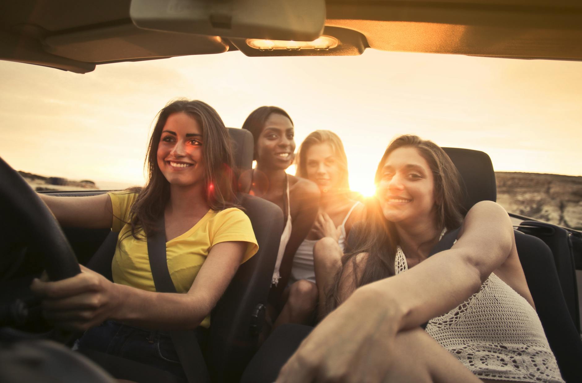 photo of women sitting on car