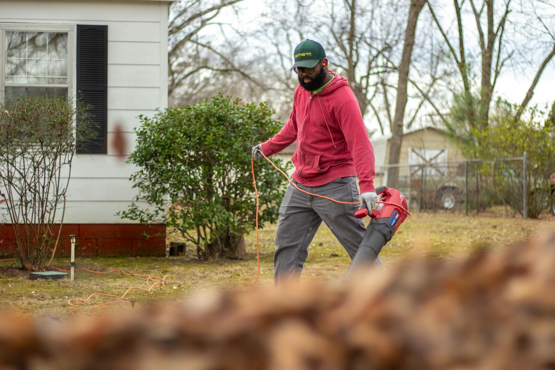 a man in red jacket holding a leaf blower